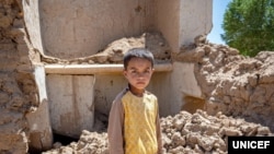 یو افغان ماشوم د زلزلو له امله وران شوي کور سره 