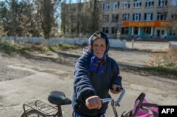 A woman holds her bicycle near a damaged school building in a village outside Mykolayiv on November 1.