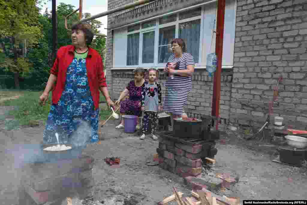 Людзі гатуюць ежу на адкрытым агні, пасёлак Новалуганскае, чэрвень 2022 году. З пачаткам поўнамаштабнага ўварваньня колькасьць ахвяр рэзка ўзрасла: зь лютага 2022-га да лістапада 2025 году Расея забіла 668 украінскіх дзяцей, а параніла – 2253