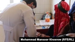 یک داکتر در شفاخانه غور سرگرم معاینه یکی از اطفال مبتلا به سوء تغذیه است.