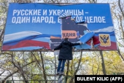 Чоловік знімає банер з періоду російської окупації у нещодавно звільненому Херсоні 14 листопада 2022 року