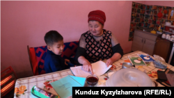 Гүлжан Молдалиева небереси менен сабак окуп жатат.