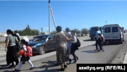 Жөндеуі бітпей жатқан "Шымкент-Алматы" жолынан ата-аналарының көмегімен өтіп бара жатқан оқушылар. Азаттық видеосынан алынған скриншот.  Шымкент, 16 сәуір 2016 жыл.