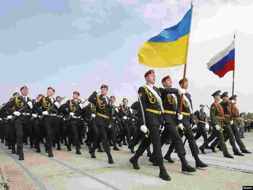 Лава з російських і українських вояків, перед якою несуть прапори обох держав. 