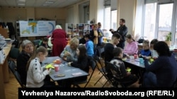 Жінки-вимушені переселенки разом зі своїми дітьми під час заняття з арт-терапії роблять обереги для українських бійців