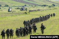 Испанские, немецкие и нидерландские военные рядом с военными вертолетами на полигоне Богата, Румыния, 14 мая 2024 года