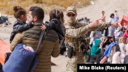 Эки кичинекей баланы көтөрүп жүргөн мигрант. Сан-Диего. 11-май, 2023-жыл.