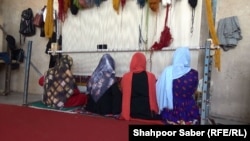 تعدادی از زنانی که در برنامه اموزش حرفه در ولایت هرات شامل اند و قالین بافی می آموزند