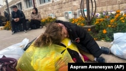 Nagorno-Karabakh - A child sleeps on a bag with clothes and other belongings as people hoping to leave Karabakh gather in Stepanakert, September 25, 2023.