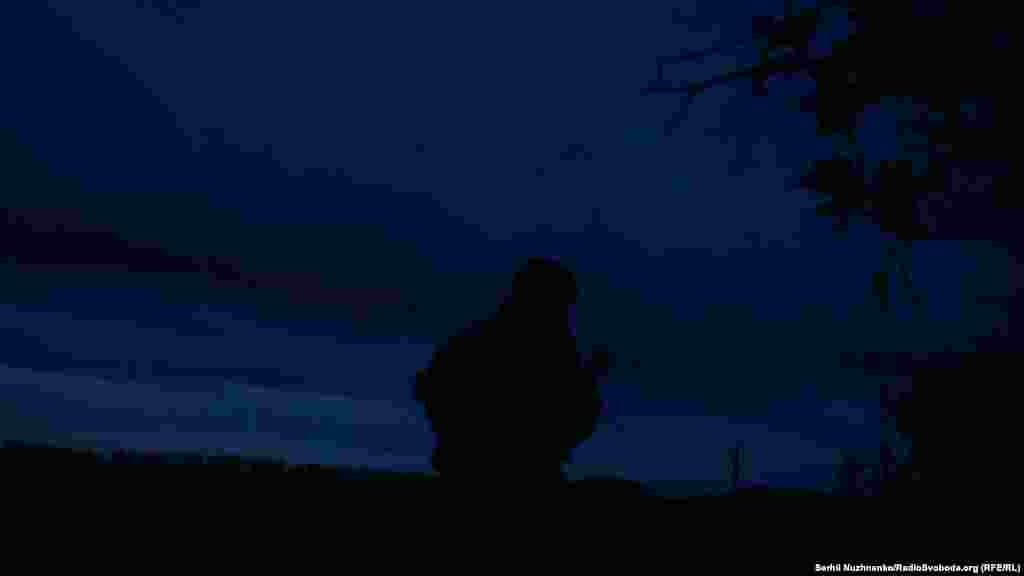 With the sounds of machine-gun fire and explosions ringing out, a Ukrainian soldier slowly advances under the cover of darkness toward Russian positions.