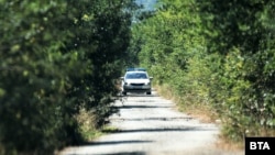 Полицейска кола охранява мястото край село Лозен, където беше намерен един от труповете през уикенда.