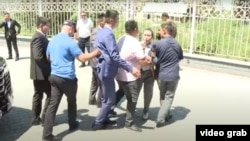 Бірнеше ер адам Азаттық тілшісі Мейірім Бақытжанға кедергі келтіріп жатқан сәт. Алматы, 13 шілде 2023 жыл. 