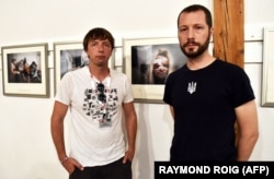 Українські фотографи Євген Малолєтка (ліворуч) і Мстислав Чернов позують перед своїми фотографіями на виставці «Маріуполь, Україна» під час Міжнародного фестивалю фотожурналістики Visa pour l'Image. Місто Перпіньян, Франція, 31 серпня 2022 року