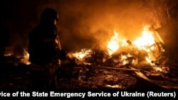 A firefighter extinguishes a fire in a parking area sparked by the falling remains of a Russian missile in Kyiv on May 16. 