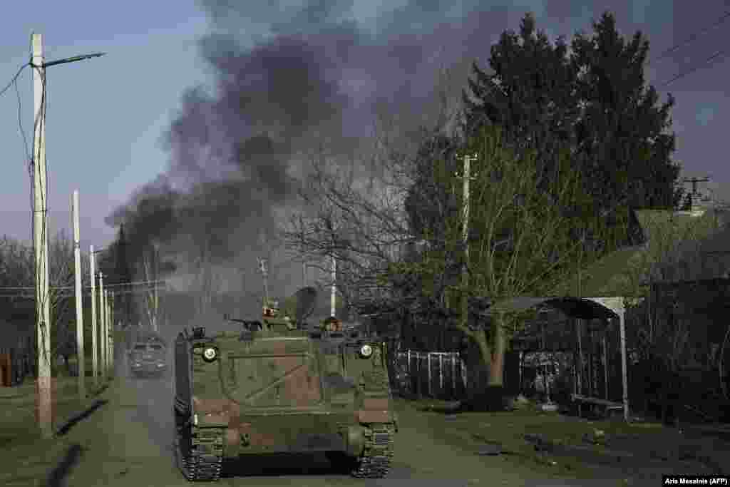 Smoke rises from the city of Bakhmut as Ukrainian forces travel through Chasiv Yar on an M113 armored personnel vehicle. Chasiv Yar, which is perched on a hill a few kilometers to the west, is most likely to become the next defense line against Moscow&#39;s forces.
