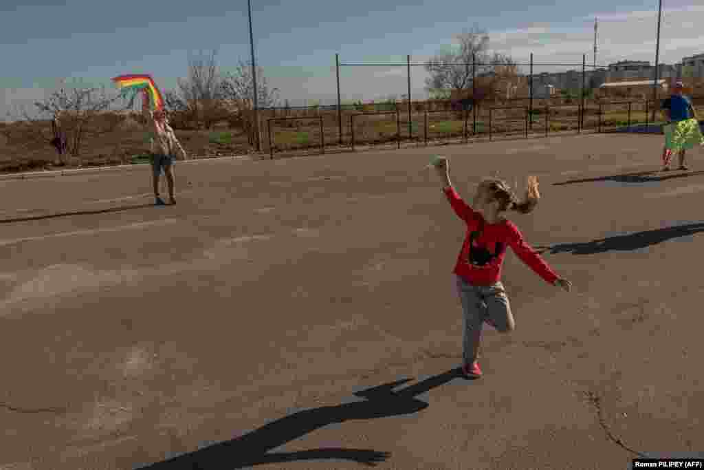 Дівчинка запускає повітряного змія з бабусею під сонячними променями під вечір у Херсоні, 29 жовтня 2023 року &nbsp;