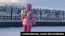 Женщина, с прикрепленной к спине надписью «кара халык» или «простой народ», 19 января 2024 г.