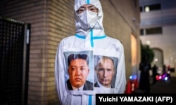 Чоловік у захисному костюмі з портретами лідера Північної Кореї Кім Чен Ина та президента Росії Володимира Путіна під час святкування Гелловіну. Токіо, Японія, 30 жовтня 2022 року