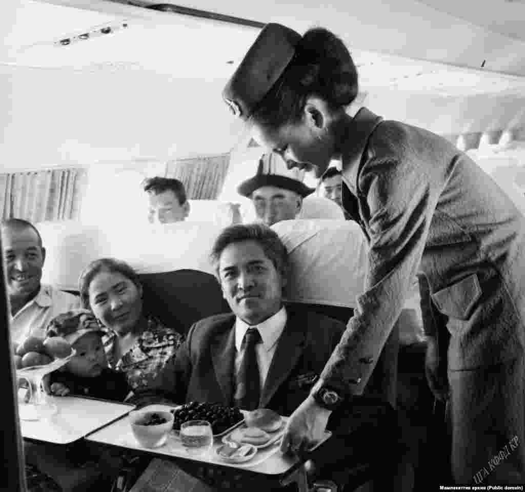 Учакта отурган жүргүнчүлөр жана стюардесса.