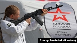 Агітаційниця тримає макет автомата АК-74 на мобільному пункті вербування у лави російської армії в окупованому Росією Сімферополі. Окупований Крим, 15 квітня 2023 року