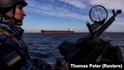 Кара деңизде жүк ташуучу кеме өтүп баратканда кайгуулда турган украин аскери.  7-февраль, 2024-жыл