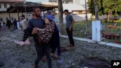 Газадагы ооруканада болгон жардыруудан жабыркаган аялды көтөрүп бараткан жергиликтүү тургун. 17-октябрь, 2023-жыл.