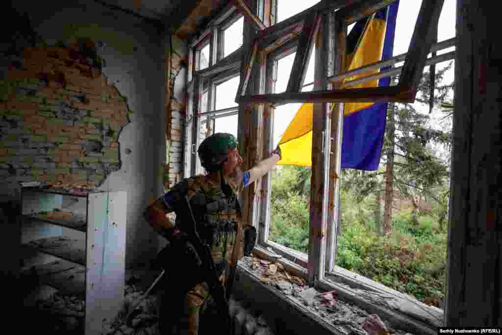 A Ukrainian soldier on June 17 straightens his country&#39;s national flag, which was hung from the House of Culture in the newly liberated village of Blahodatne, near the front line in the Donetsk region. The village was among the first to be recaptured during the early stages of Kyiv&#39;s counteroffensive.