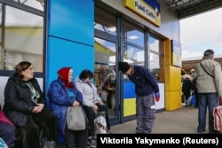 Fuminori Tsuçiko 27-nji aprelde Harkiwdäki kafesiniň daşynda ýerli ýaşaýjylar bilen salamlaşýar.