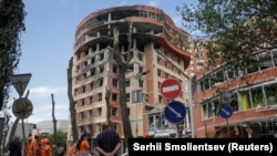 Орус армиясынын ракеталык соккусунан жабыркаган соода борборунун жанында иштеп жаткан муниципалдык жумушчулар. Украина. 14-июнь, 2023-жыл. REUTERS/Сергей Смоленцев.