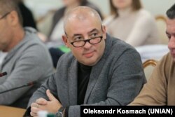 На фото від 6 грудня 2017 року тогочасний народний депутат Юрій Буглак бере участь у засіданні Комітету Верховної Ради з питань запобігання та протидії корупції, в якому він очолював підкомітет з питань запобігання і протидії політичній корупції