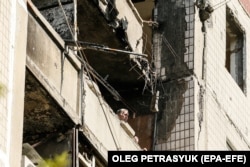 Чоловік дивиться з вікна згорілої квартири в місті Вугледар на Донеччині, 16 липня 2023 року