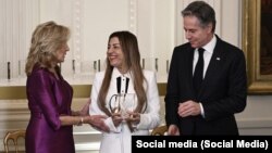 تصویر بنفشه یعقوبی در حالی که جایزه زنان شجاع سال ۲۰۲۴ را از جیل بایدن بانوی اول ایالات متحده دریافت میکند و در کنار وی انتونی بلینکن وزیر خارجه ایالات متحده نیز ایستاده است. 