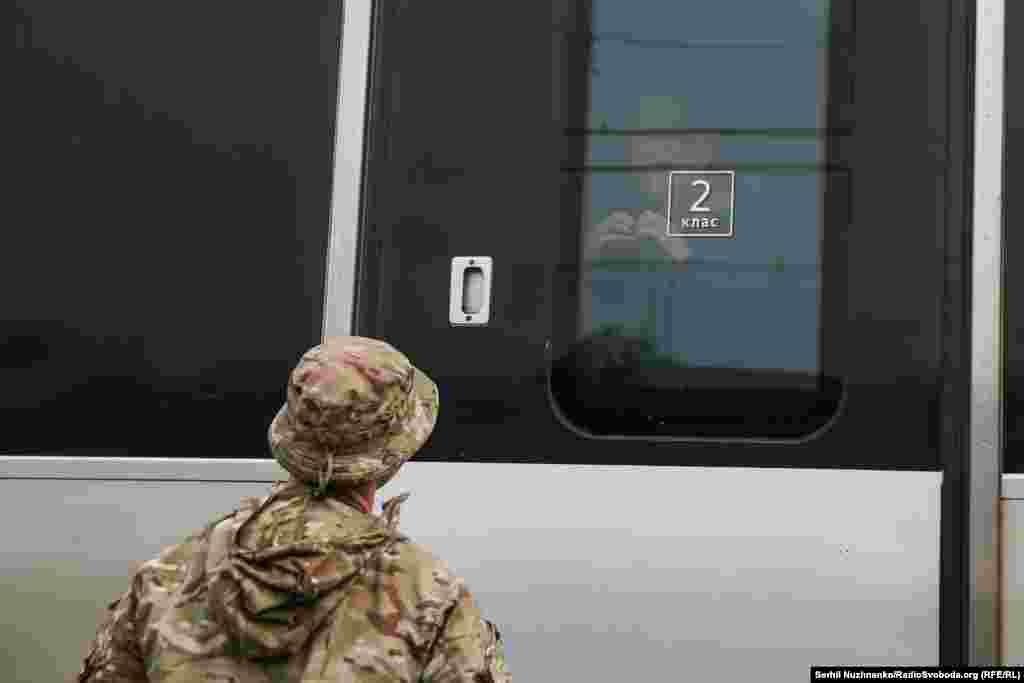 Женщина складывает кисти рук в форме сердца в окне поезда незадолго до его отправления