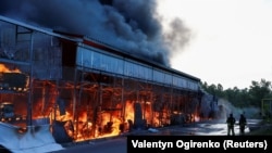 Пожарные тушат огонь у торгового центра, пострадавшего от российского авиаудара. Харьков, Украина, 25 мая 2024 года