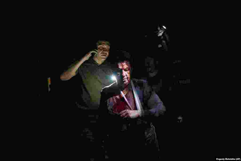 A Ukrainian policeman accompanies an injured woman, Natasha, to a waiting ambulance following a Russian missile strike. The attack damaged her home in Pokrovsk, in the Donetsk region, during the night of June 21.