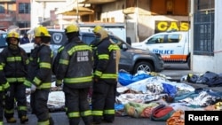 Өрт өчүрүүчүлөр имараттын ичинен алып чыккан сөөктөрдүн жанында турушат. Йоханнесбург, Түштүк Африка. 31-август, 2023-жыл. 