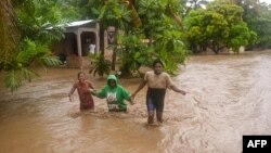 Гаитинин Леоган шаарынын тургундары суу каптаган көчөдө баратышат. 3-июнь, 2023-жыл.