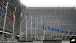 Belgium - People walk past EU headquarters prior to an EU summit in Brussels, Thursday, Oct. 26, 2023.