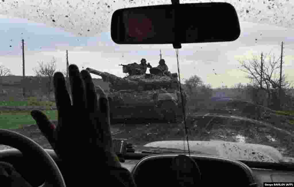 Ukrainian soldiers wave to each other along a road near the city of Bakhmut on April 8. The brutal battle for &quot;Fortress Bakhmut&quot; is being called the bloodiest infantry battle since World War II.
