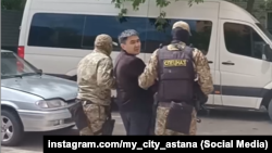 People wearing camouflage lead Kazakh opposition activist Aidar Syzdykov toward an unmarked bus in Astana on May 16.