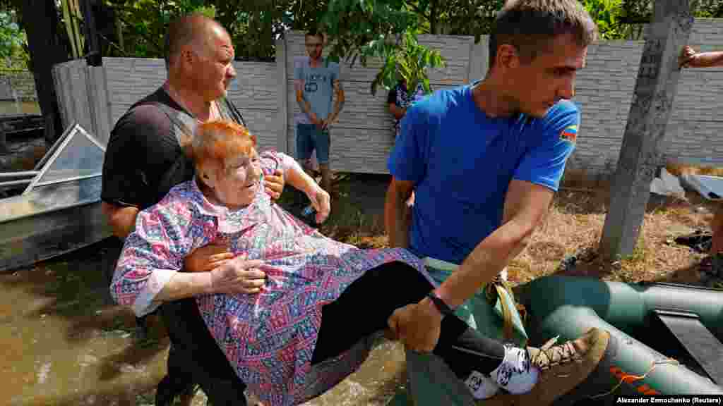 A member of Russia&#39;s Emergency Ministry and a local resident carry an elderly woman from the flooded town of&nbsp;Hola Prystan on June 8 following the breach of the Kakhovka dam. The Russian-controlled eastern bank of the Dnieper River has been hardest hit by flooding, according to Ukrainian officials.