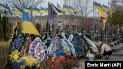 Жінка доглядає за могилою родича, загиблого у війні РФ проти України, на цвинтарі в Бучі, архівне фото