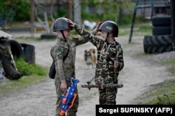 10-річний Максим і 6-річний Валентин грають у війну в селі Стоянка на Київщині, яке було певний час окуповане російськими військами на початку російського масштабного вторгнення, 11 травня 2023 року
