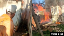 Тажикстандык мигрант өрттөнүп жаткан вагондорду карап турат. Москва облусу.