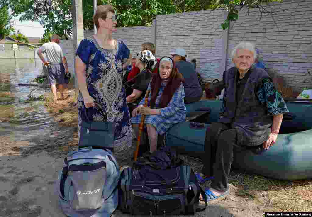 People sit on an inflatable boat after being evacuated from Hola Prystan.