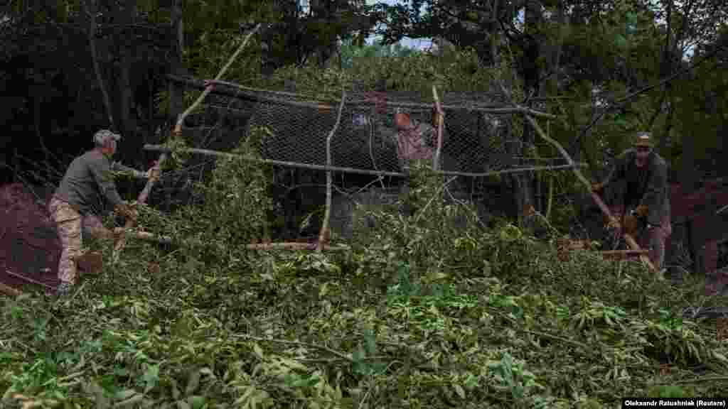 Tree branches are used to conceal the howitzer from enemy drones.