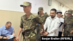 Азамат Ишенбеков менен Актилек Капаров Ленин райондук сотуна алынып келаткан учур. 7-июнь, 2024-жыл.