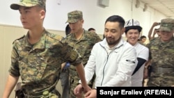 Азамат Ишенбеков менен Актилек Капаров Ленин райондук сотуна алынып келаткан учур. 7-июнь, 2024-жыл.