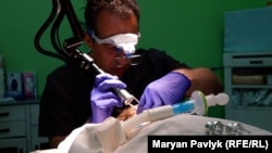 Лікар Олександр Туркевич прибирає з обличчя дитини порохові опіки