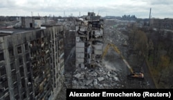 Екскаватор зносить багатоповерховий житловий будинок в Маріуполі, зруйнований під час нападу Росії. Фото від 15 лютого 2023 року